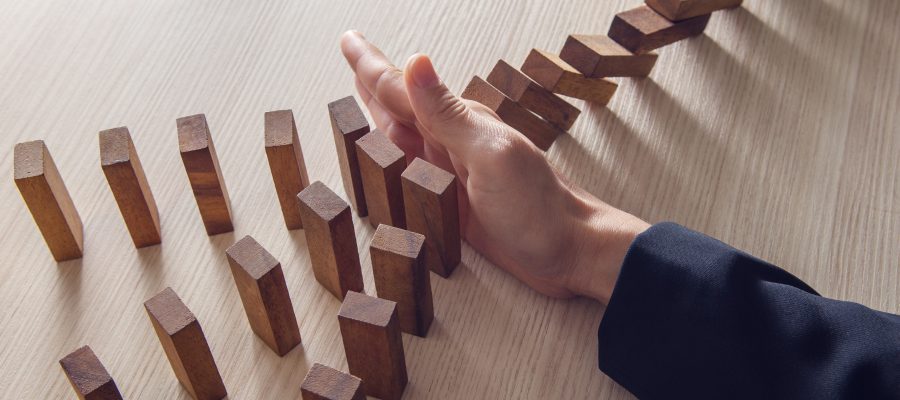 Businesswoman hand stopping the domino wooden effect concept for business.